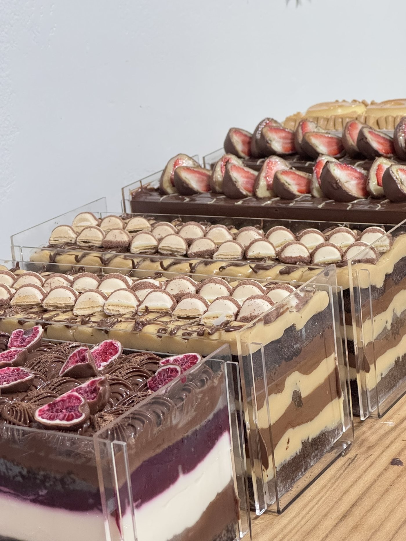 Naked cake de frutas vermelhas com creme e camadas de chocolate, ao lado de outras variedades